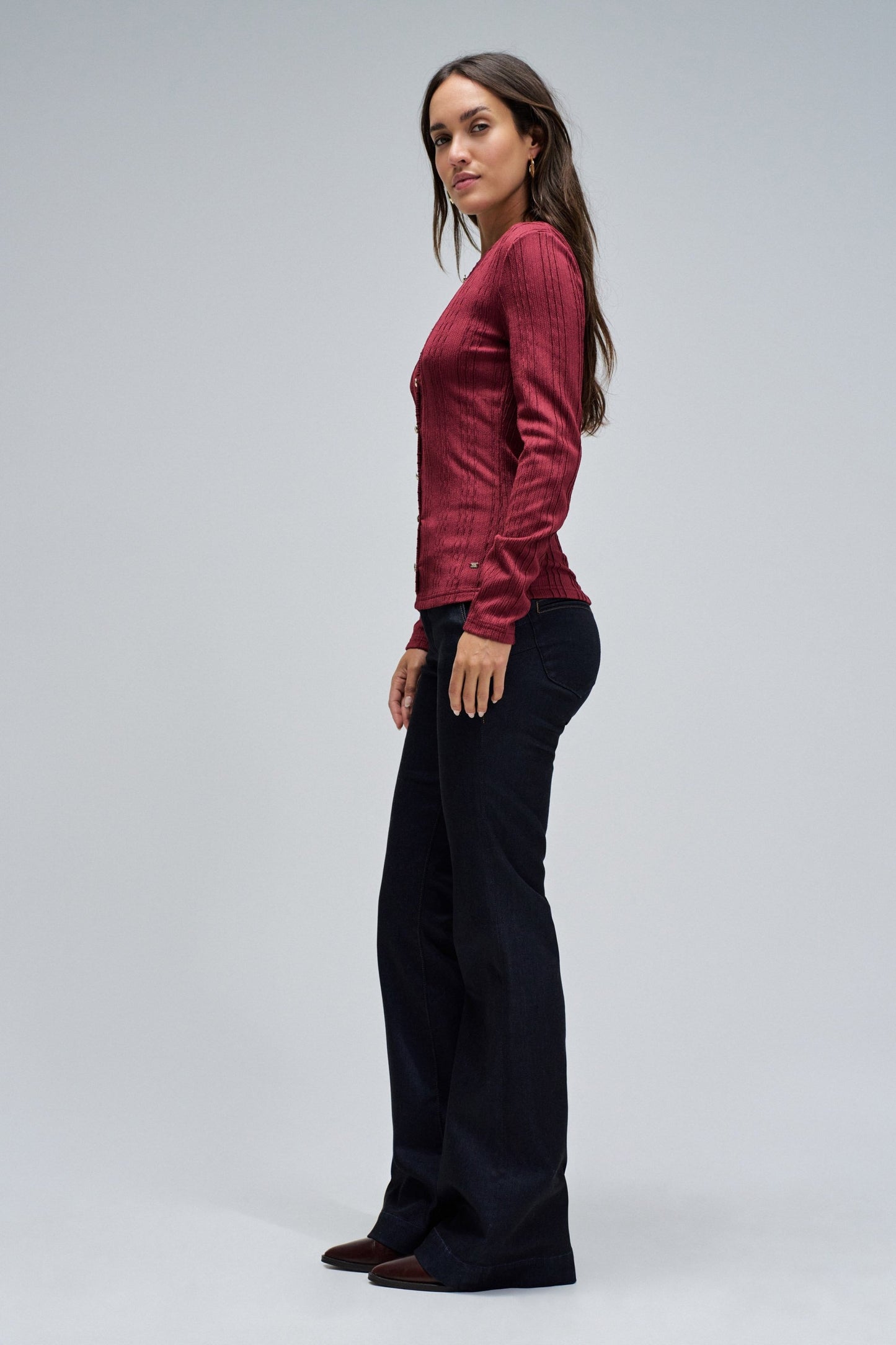 Woman wearing a red top and black pants on a gray background