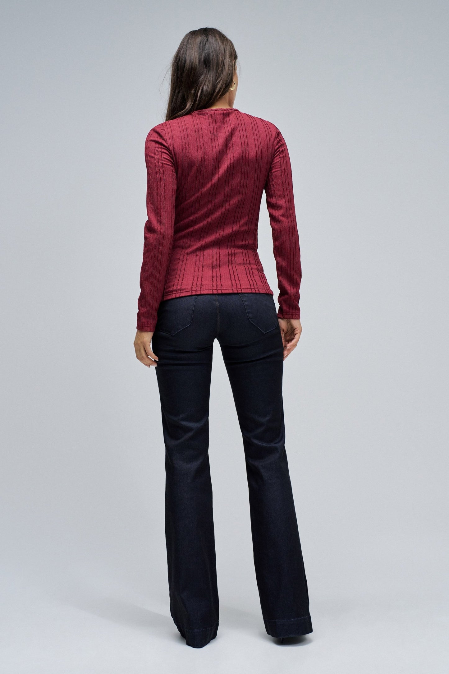 Person wearing a red patterned top and black pants on a gray background