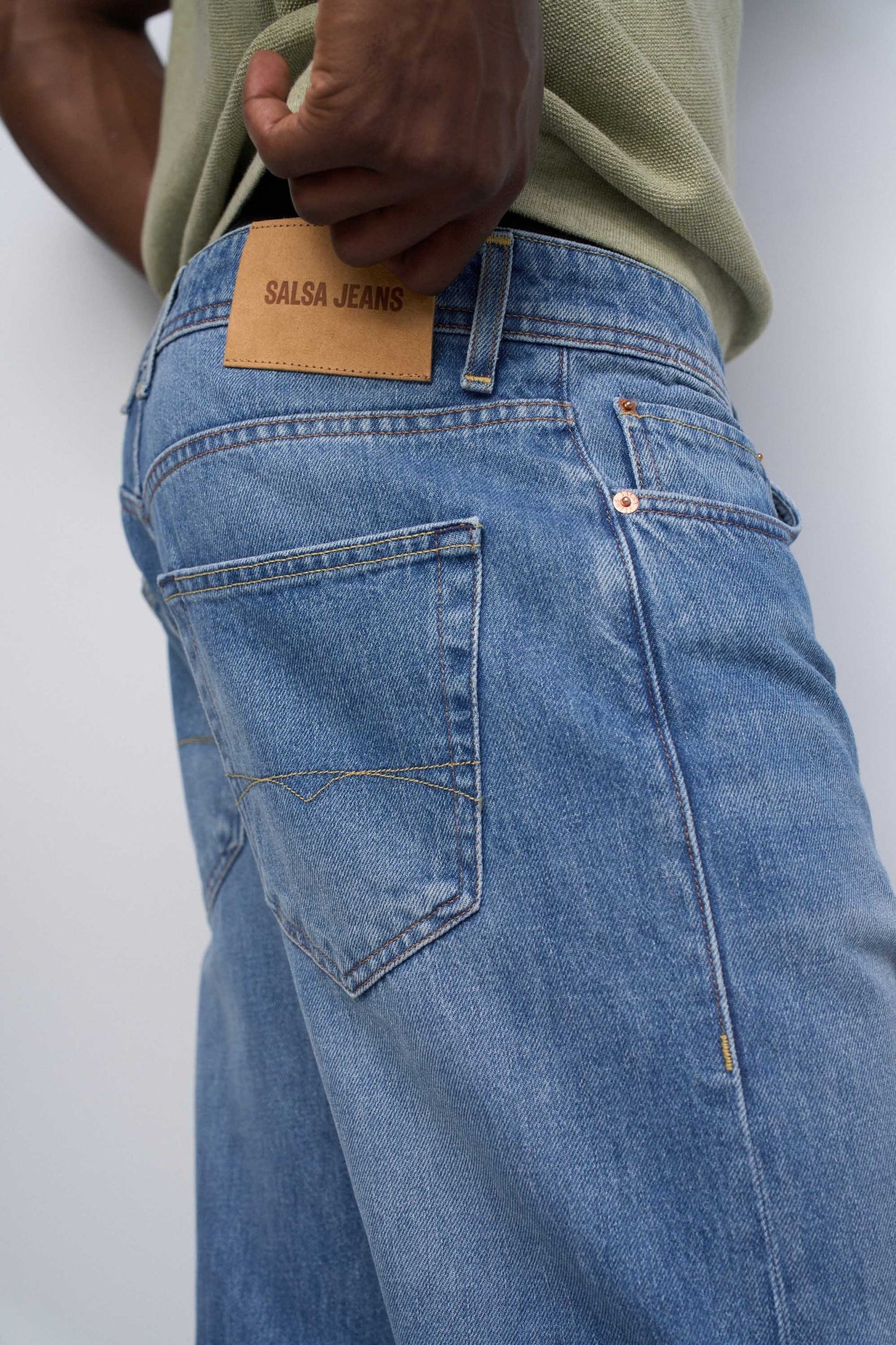 Close-up of blue jeans with a visible brand label on a white background