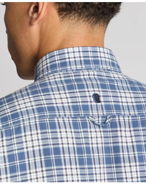Close-up of a person wearing a blue and white checkered shirt with a brand logo on a gray background