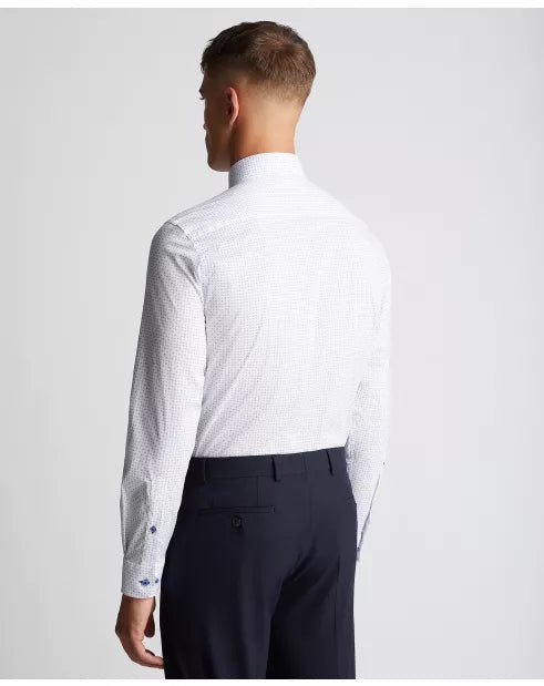 Man wearing a white dress shirt with a subtle pattern and dark pants on a light gray background