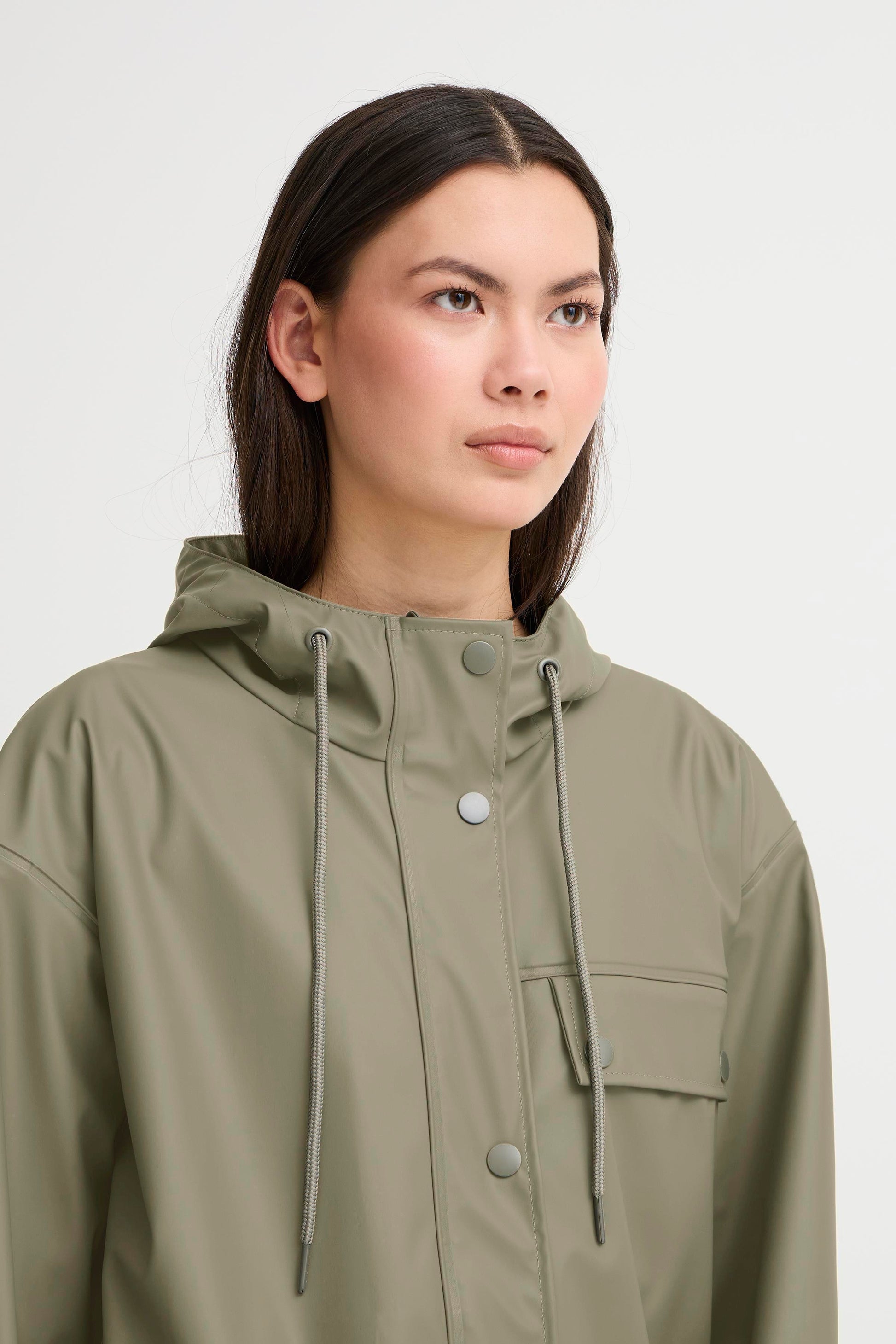 Woman wearing a green raincoat against a white background