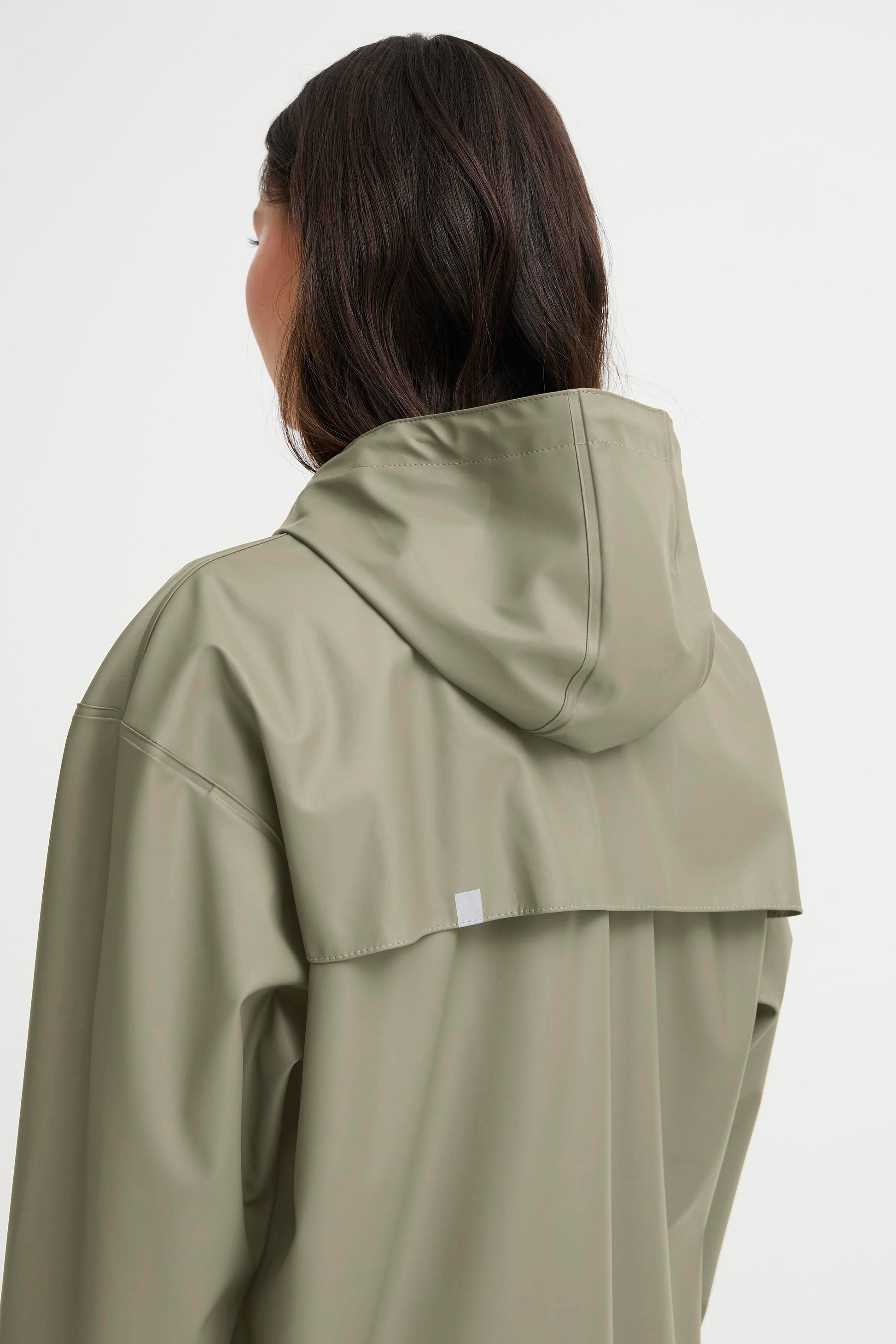 Person wearing a light green raincoat on a white background