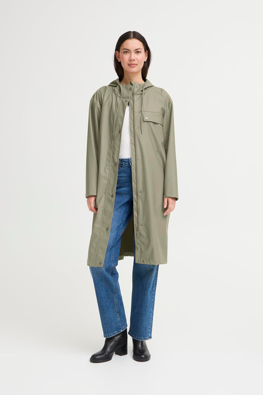 Woman wearing a long green coat on a white background