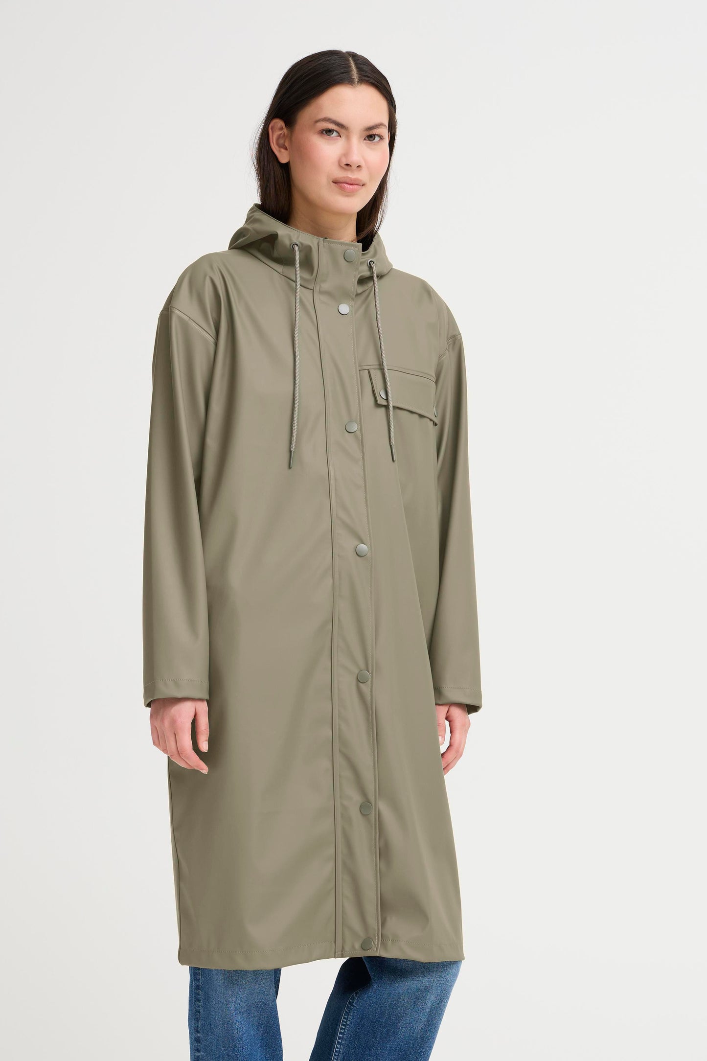 Woman wearing a long green raincoat on a white background