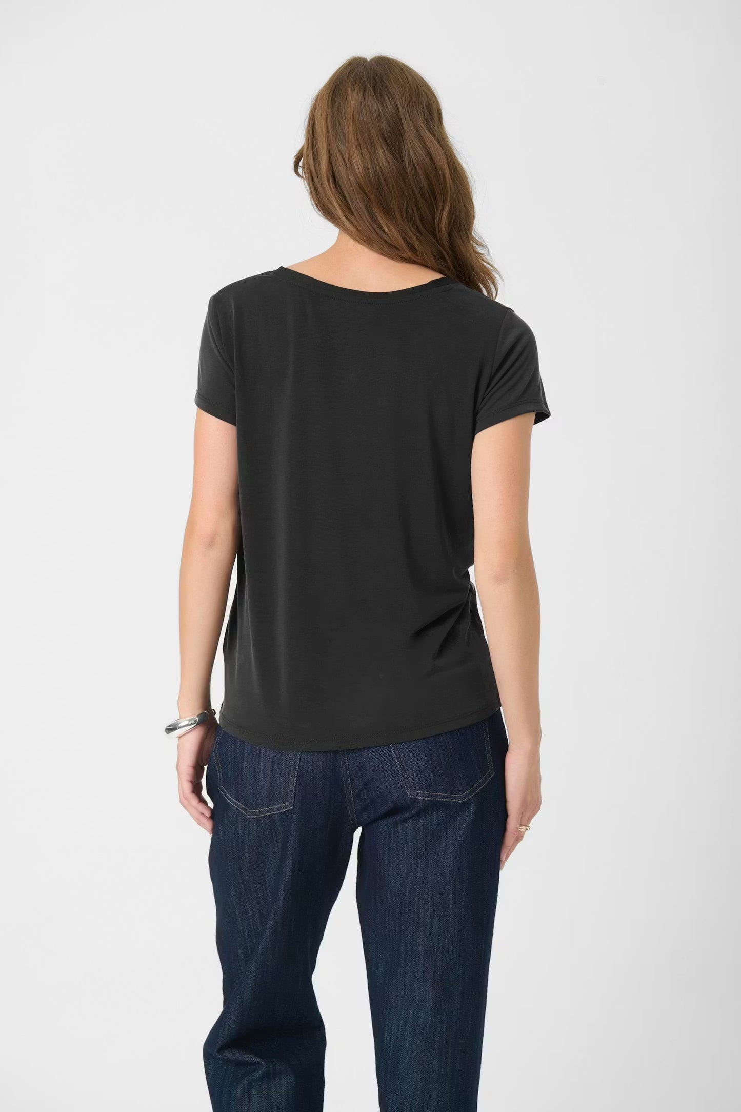 Person wearing a black t-shirt and blue jeans on a white background