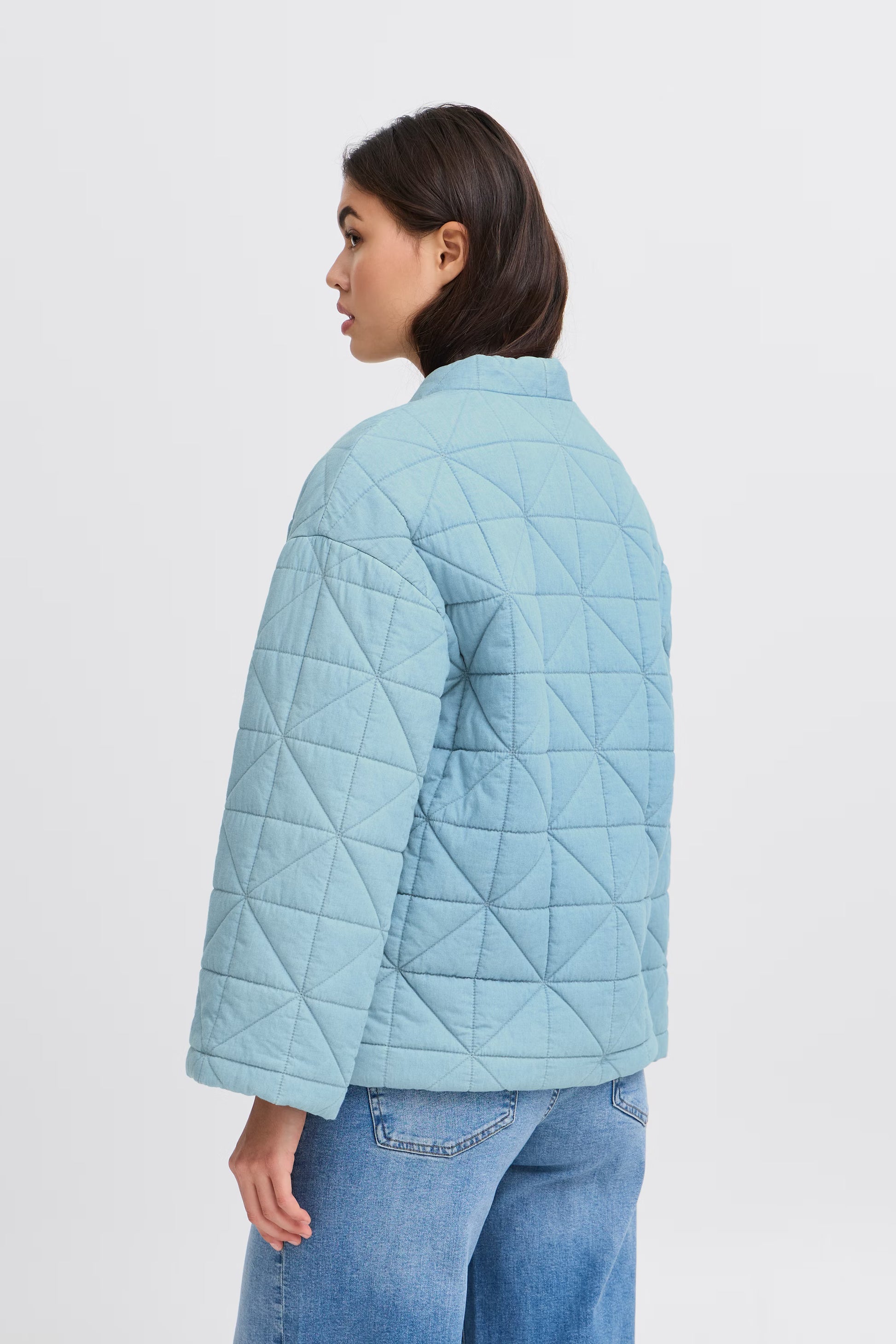 Person wearing a light blue quilted jacket on a white background
