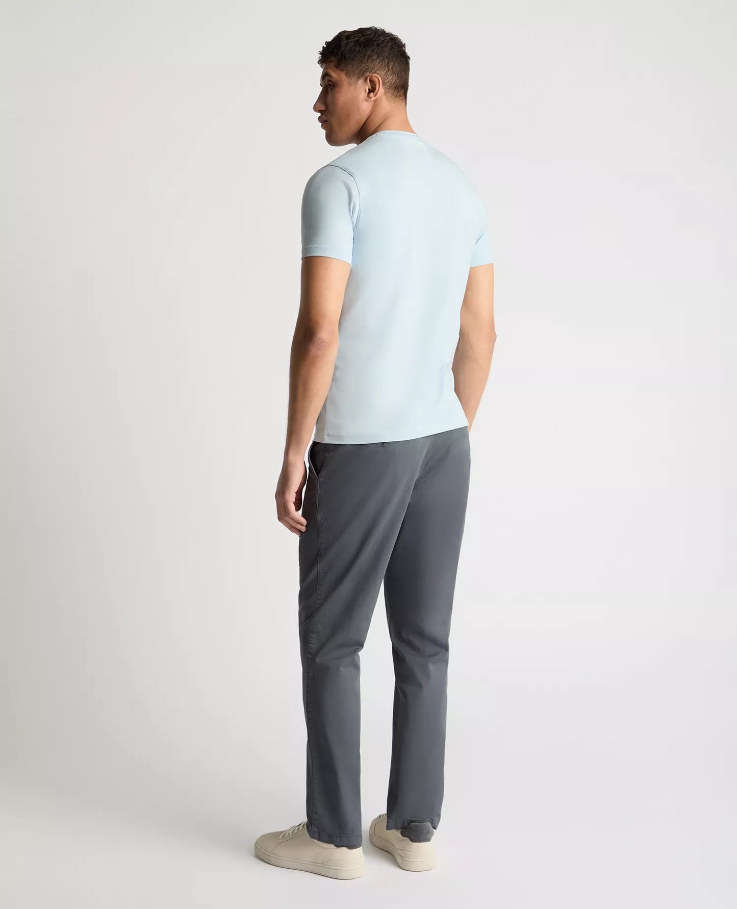 Man wearing a light blue t-shirt and gray pants on a white background