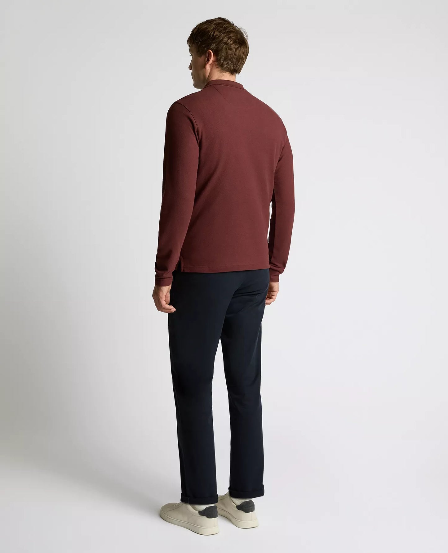 Man wearing a maroon sweater and black pants on a white background
