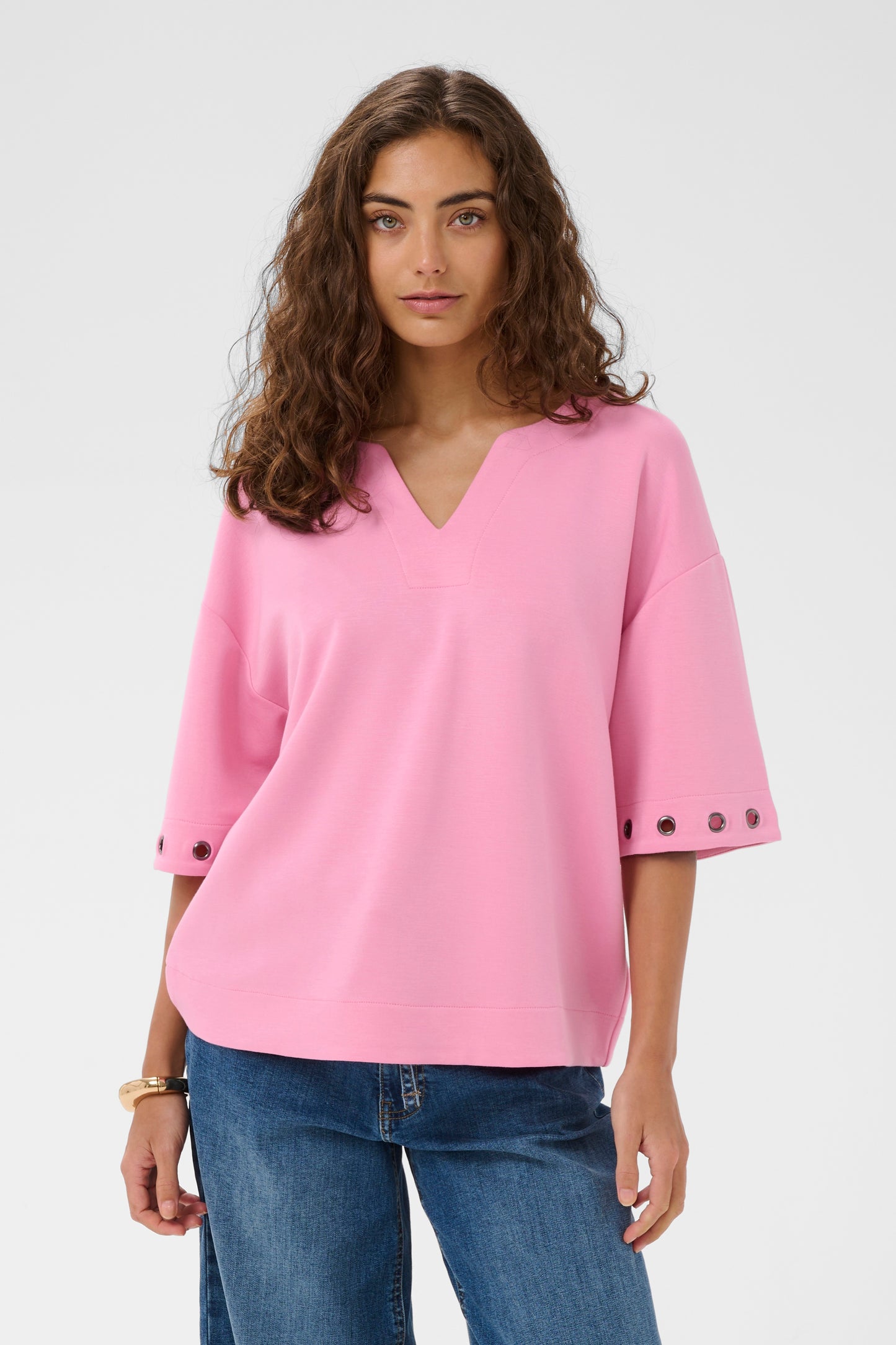 Woman wearing a pink blouse with button details on a white background