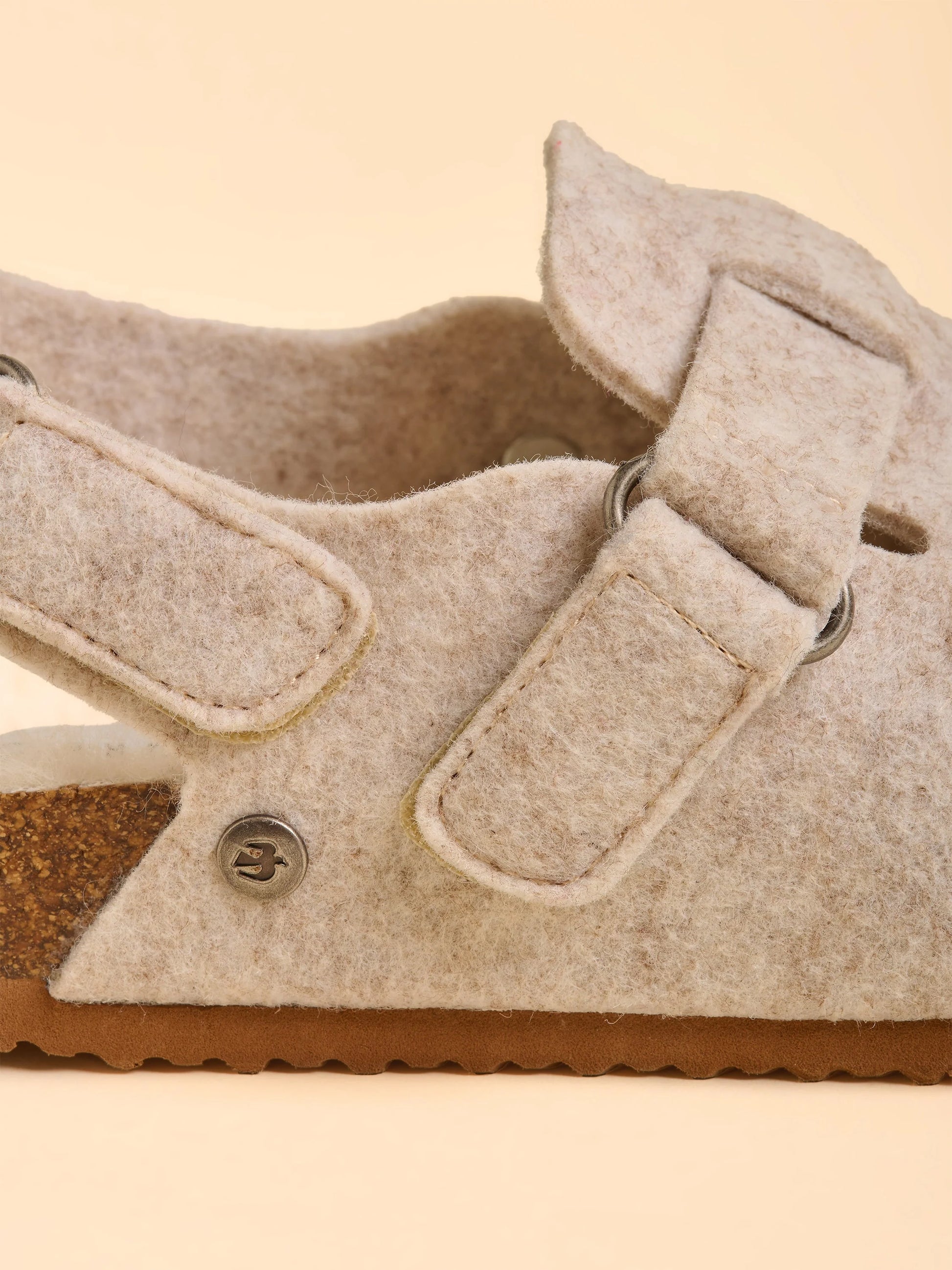 Close-up of a beige sandal with a buckle on a beige background