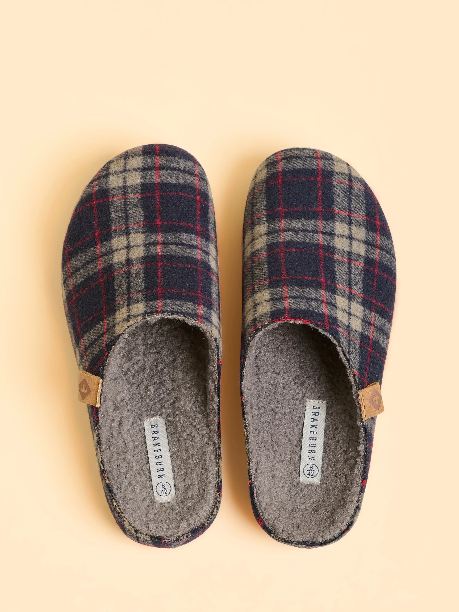 Pair of plaid slippers on a beige background