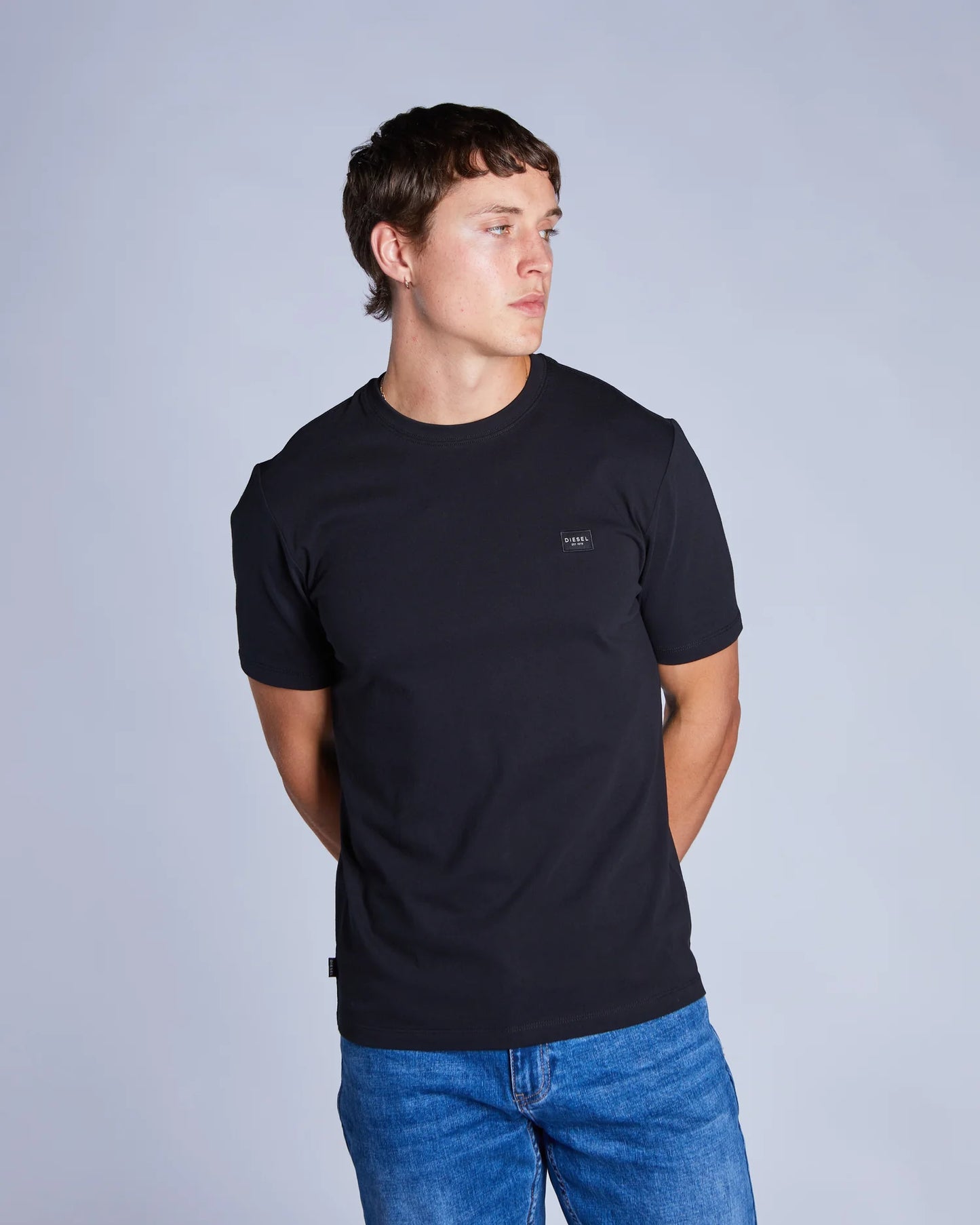 Man wearing a black t-shirt with a logo on a gray background