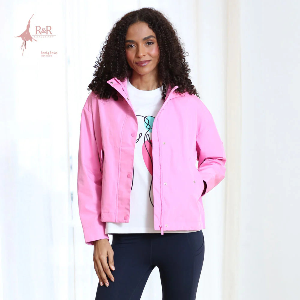 Woman wearing a pink jacket over a white shirt with a graphic design, on a plain background.