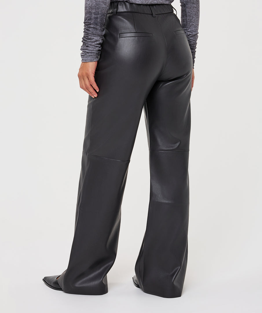 Black wide-leg faux leather pants shown from the back on a model, paired with a gray textured long-sleeve top, against a light gray studio background.