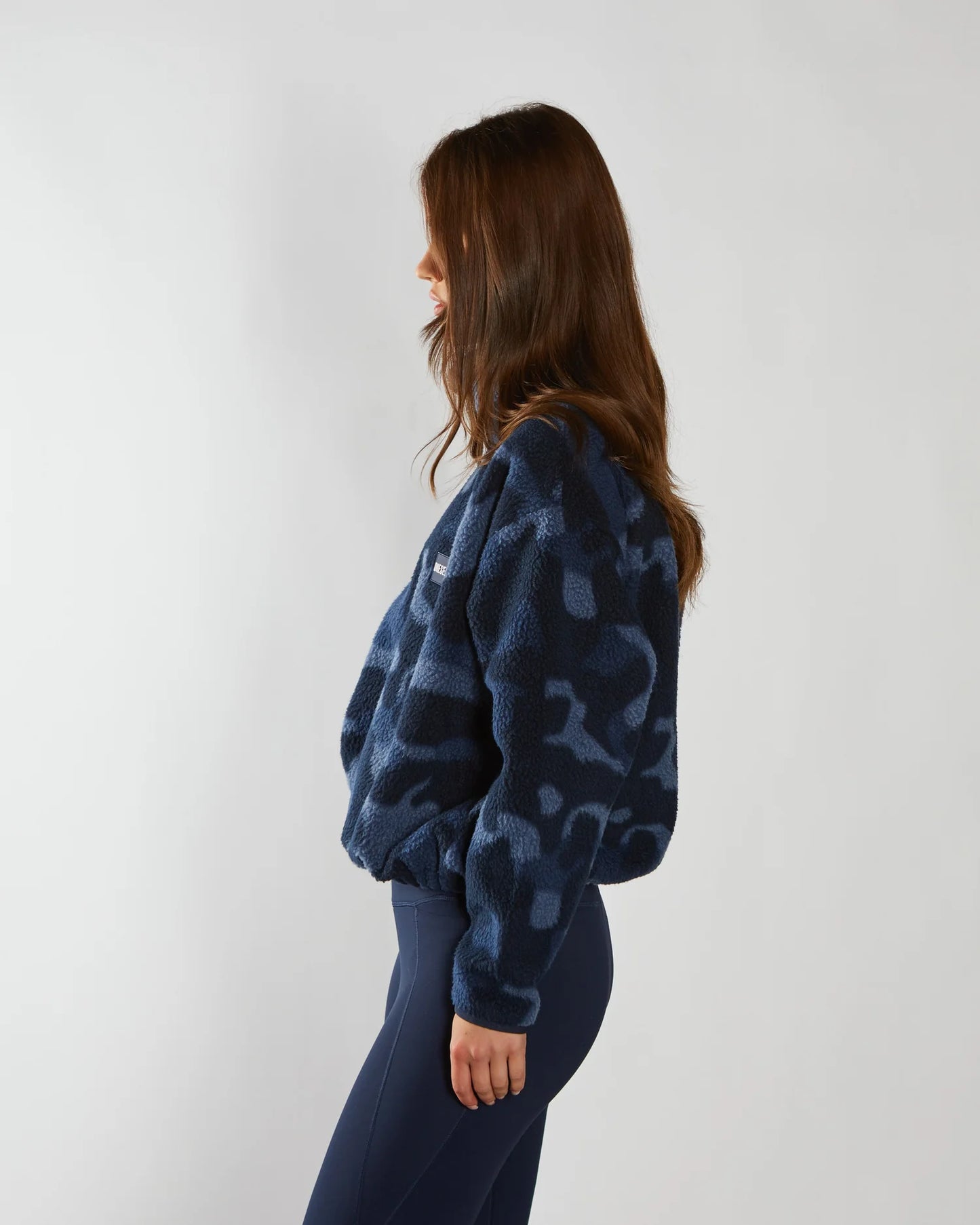 Person wearing a blue tie-dye hoodie and pants against a white background