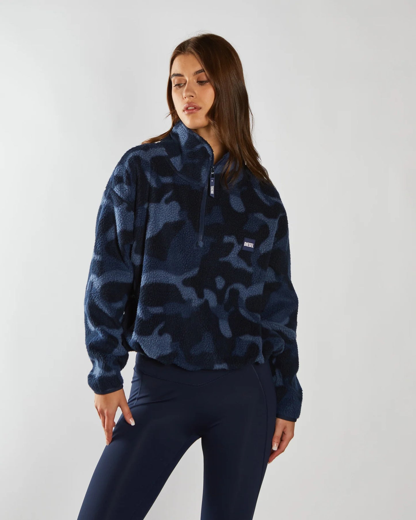 Person wearing a blue camouflage pullover with a brand logo on a white background