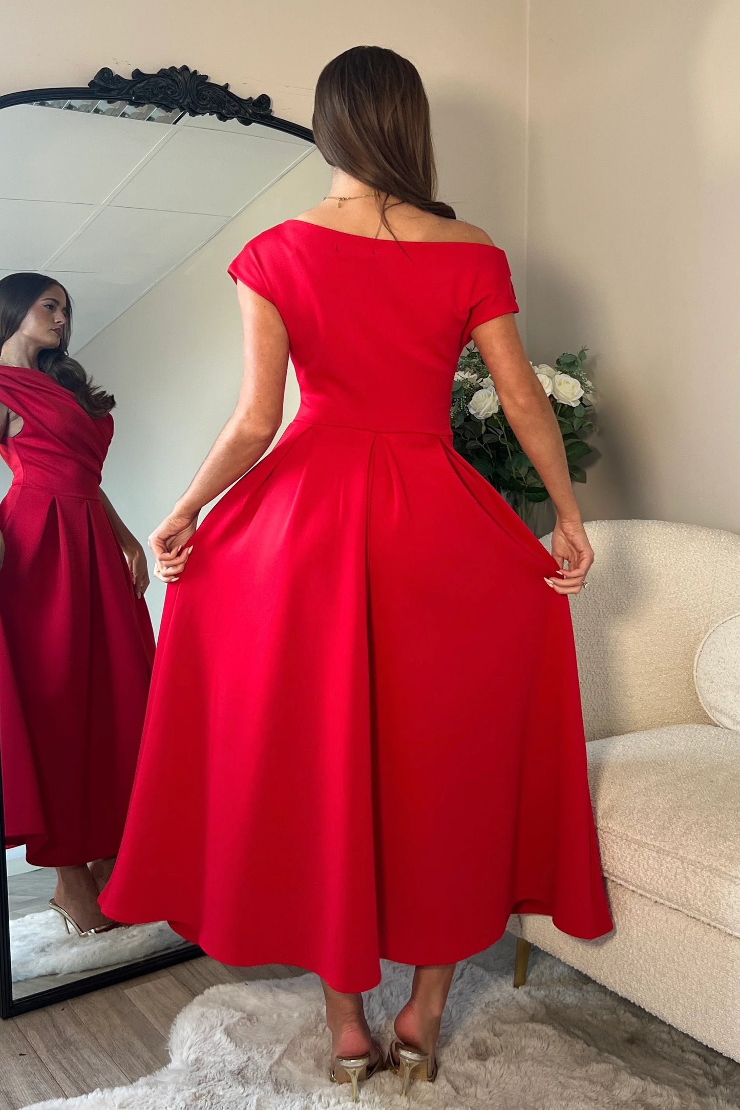 Woman wearing a red dress standing in front of a mirror.