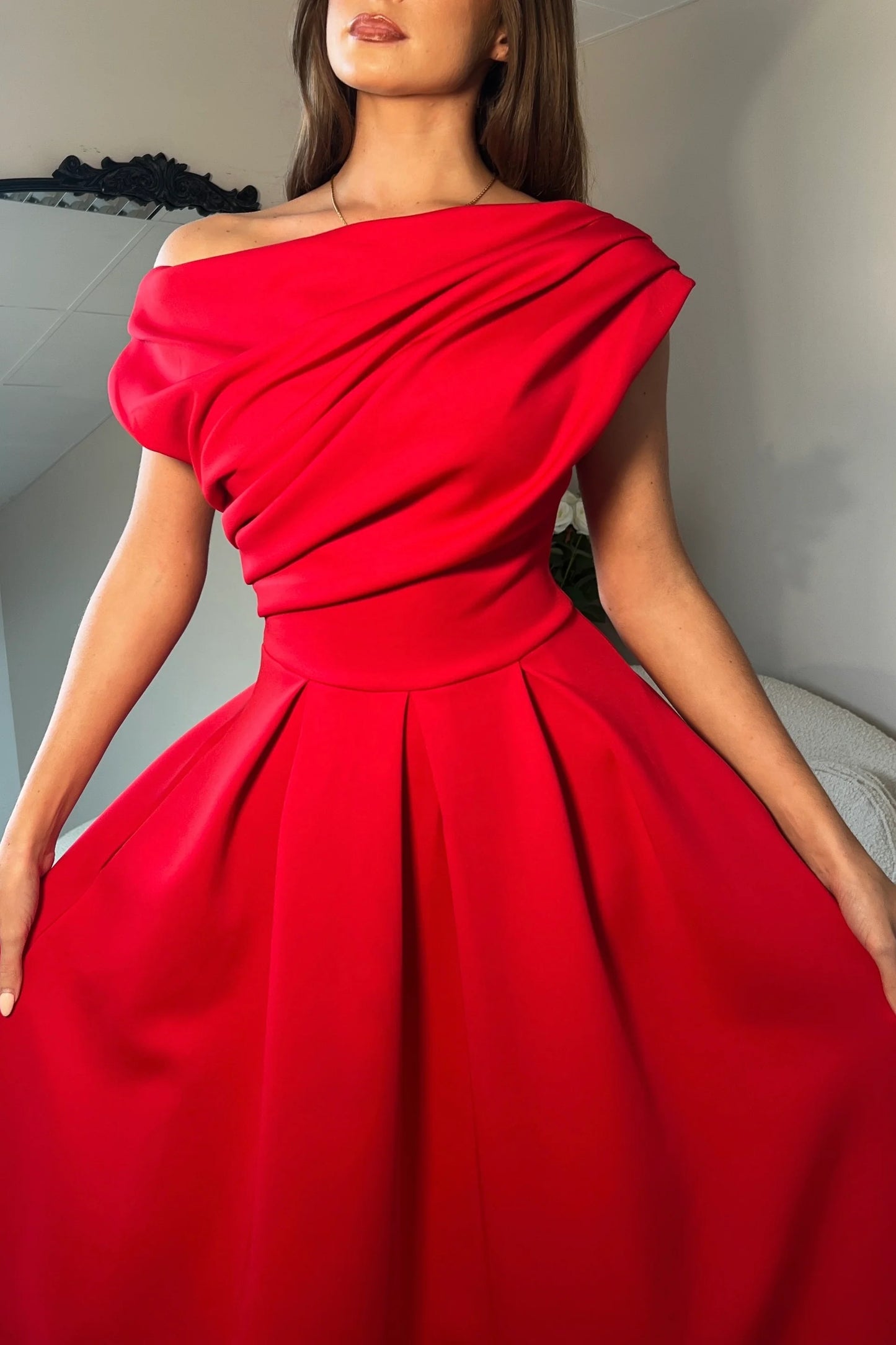 Red off-shoulder dress worn by a model against a neutral background