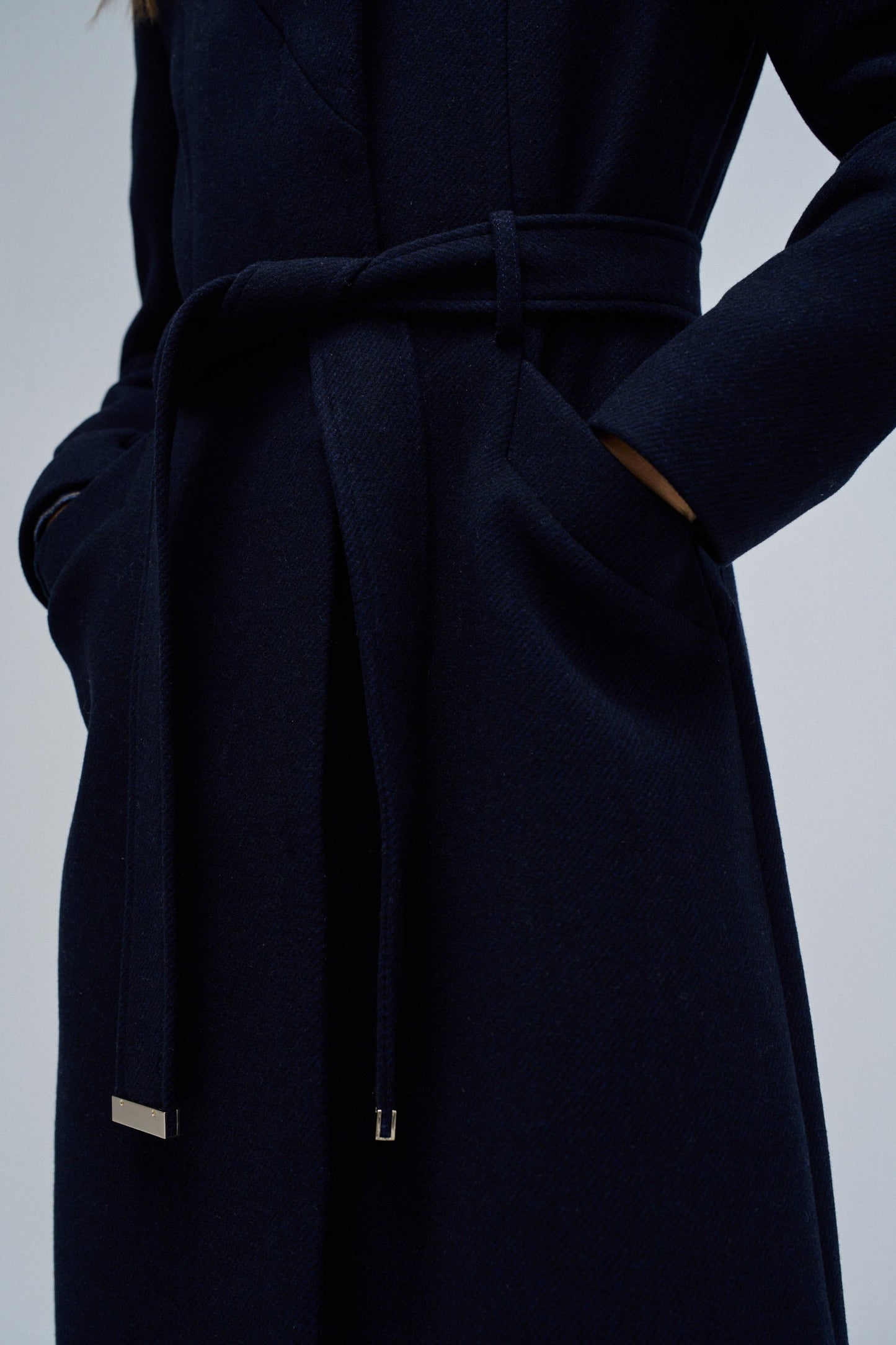 Navy blue coat with a belt on a light gray background