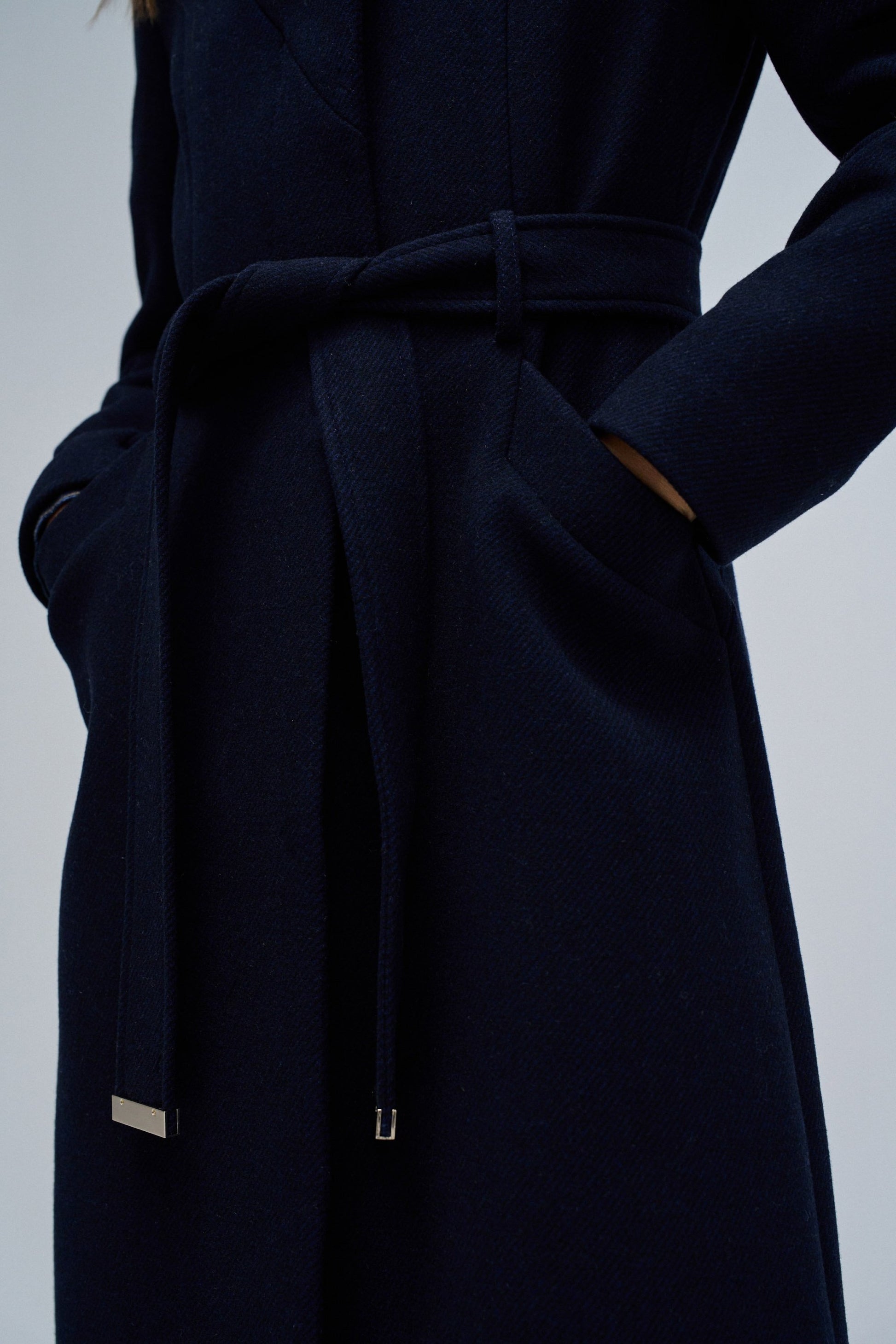 Navy blue coat with a belt on a light gray background