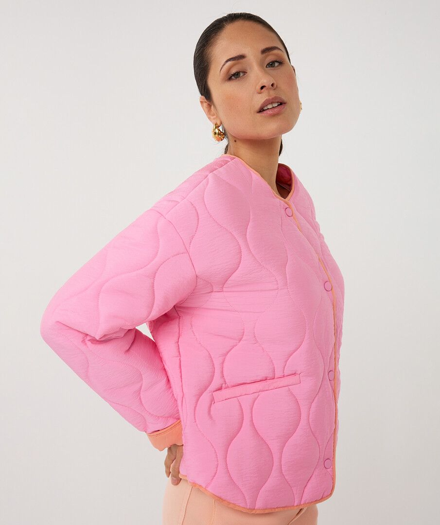 Person wearing a pink quilted jacket on a white background