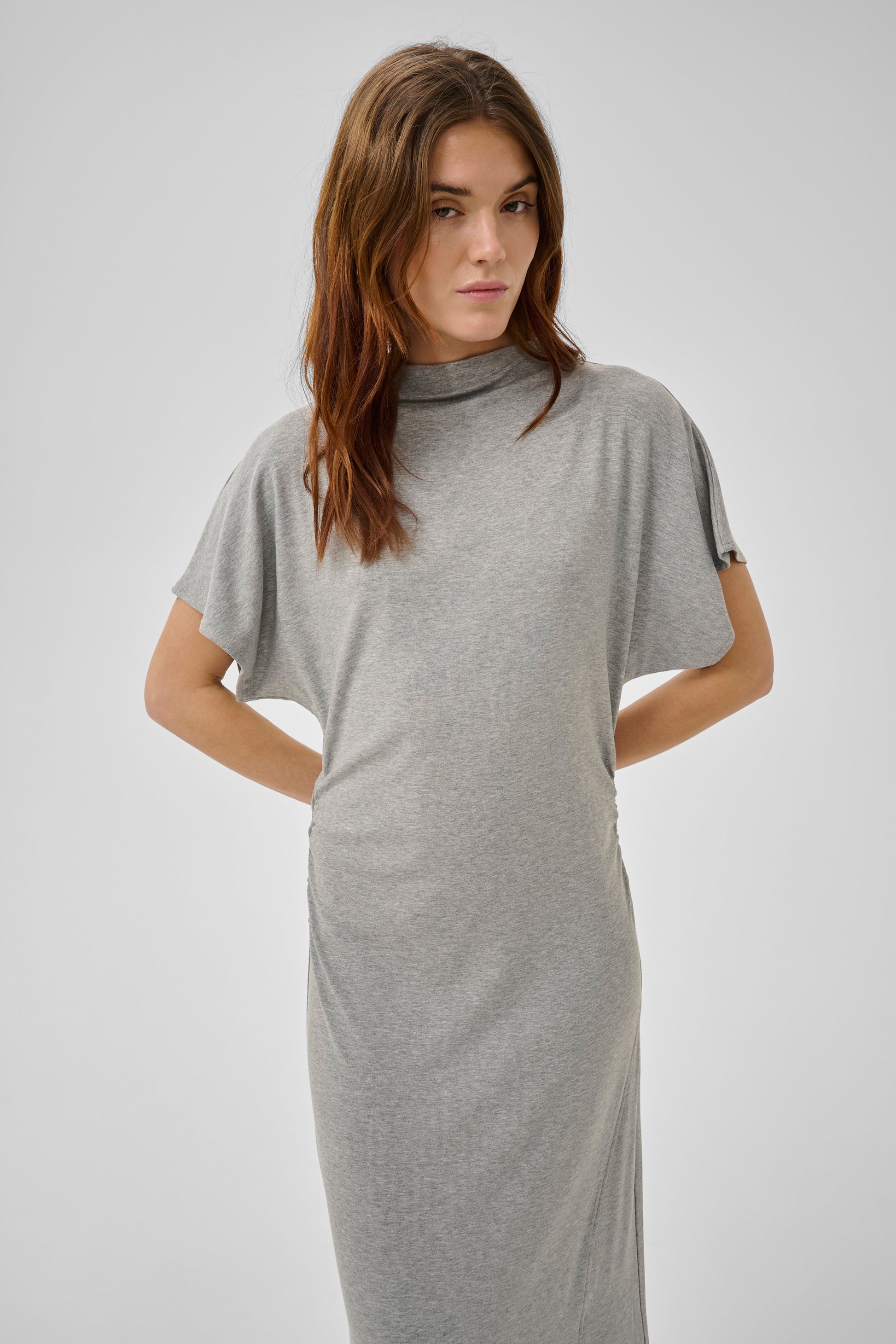 Woman wearing a gray dress against a plain background