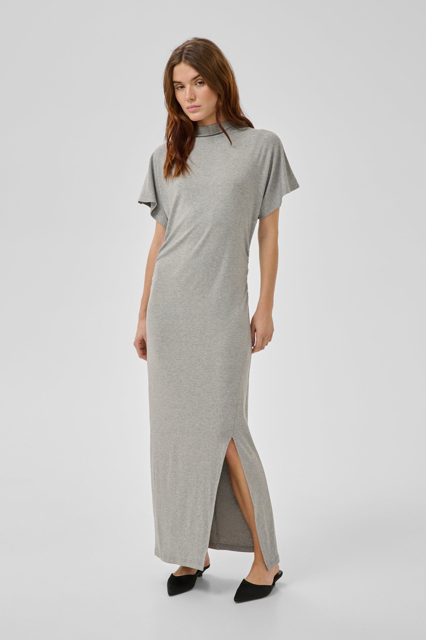 Woman wearing a gray dress with a slit on a white background