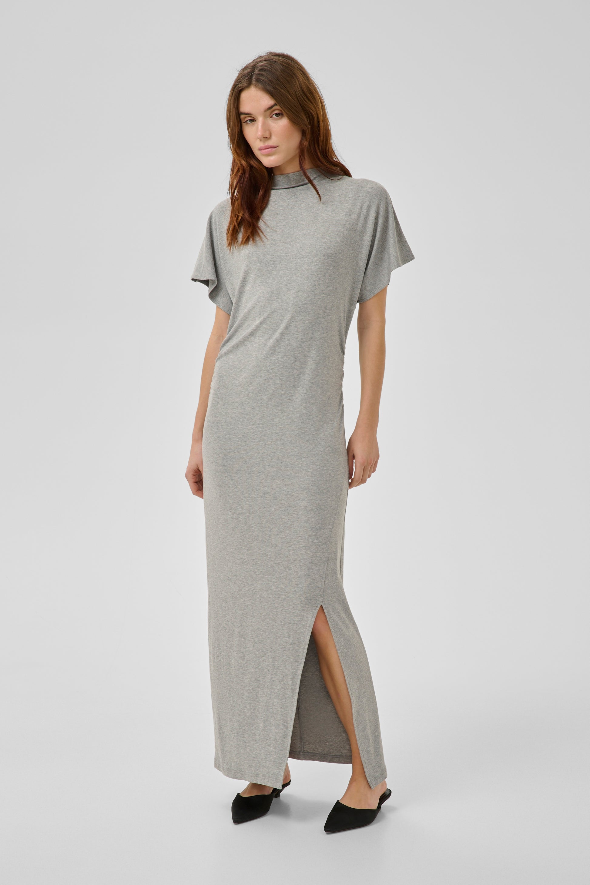 Woman wearing a gray dress with a slit on a white background