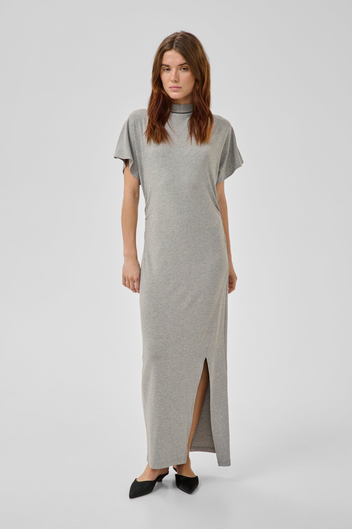 Woman wearing a gray dress with a slit on a white background
