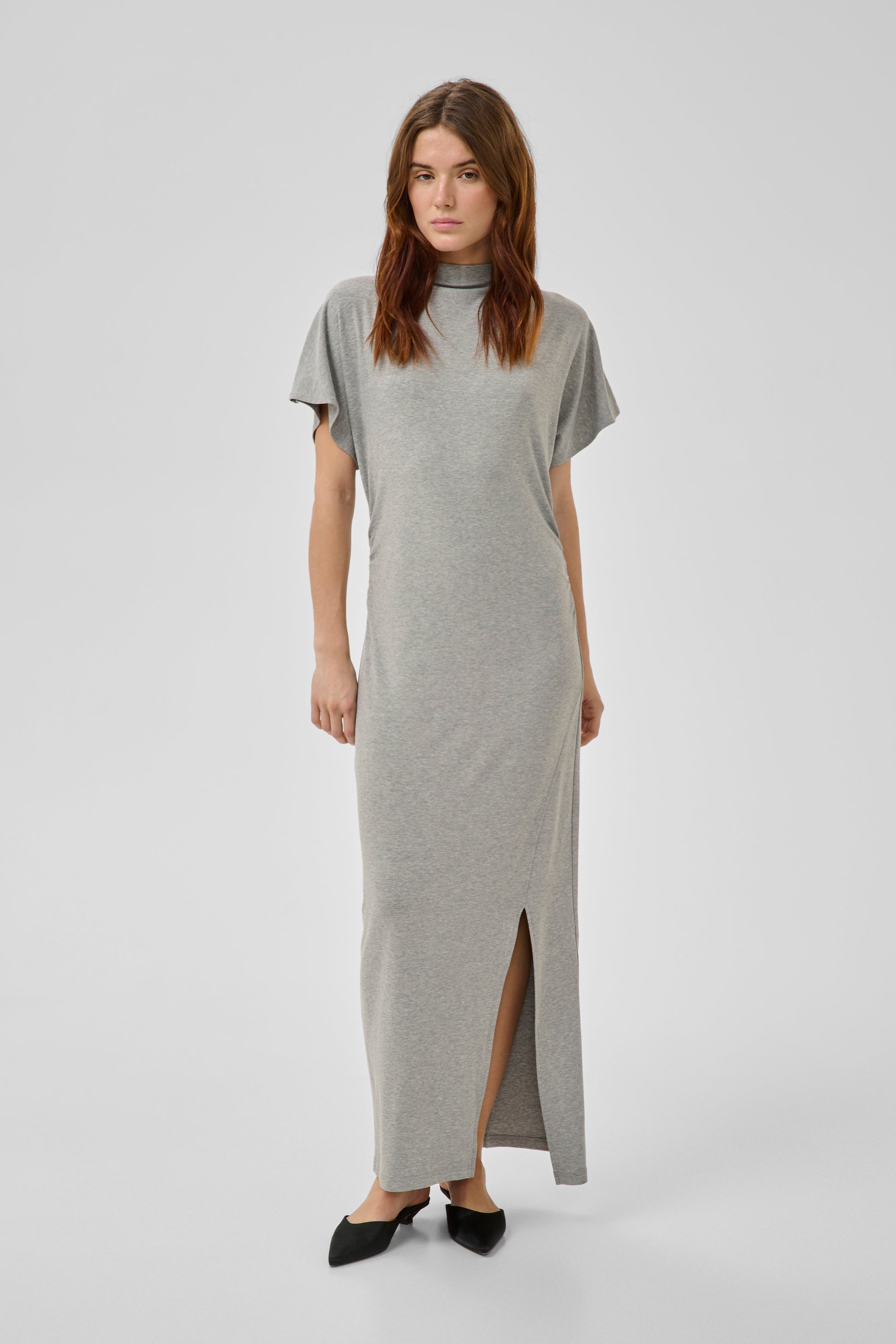 Woman wearing a gray dress with a slit on a white background