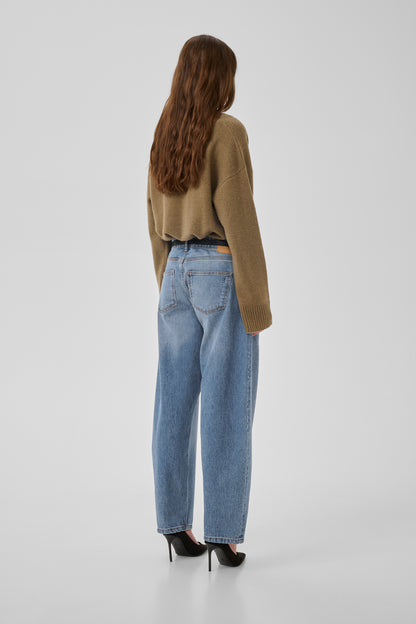 Person wearing a green sweater and blue jeans on a white background