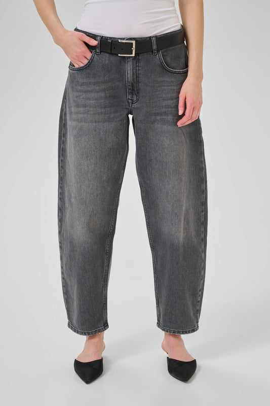 Person wearing gray jeans and a white top on a plain background