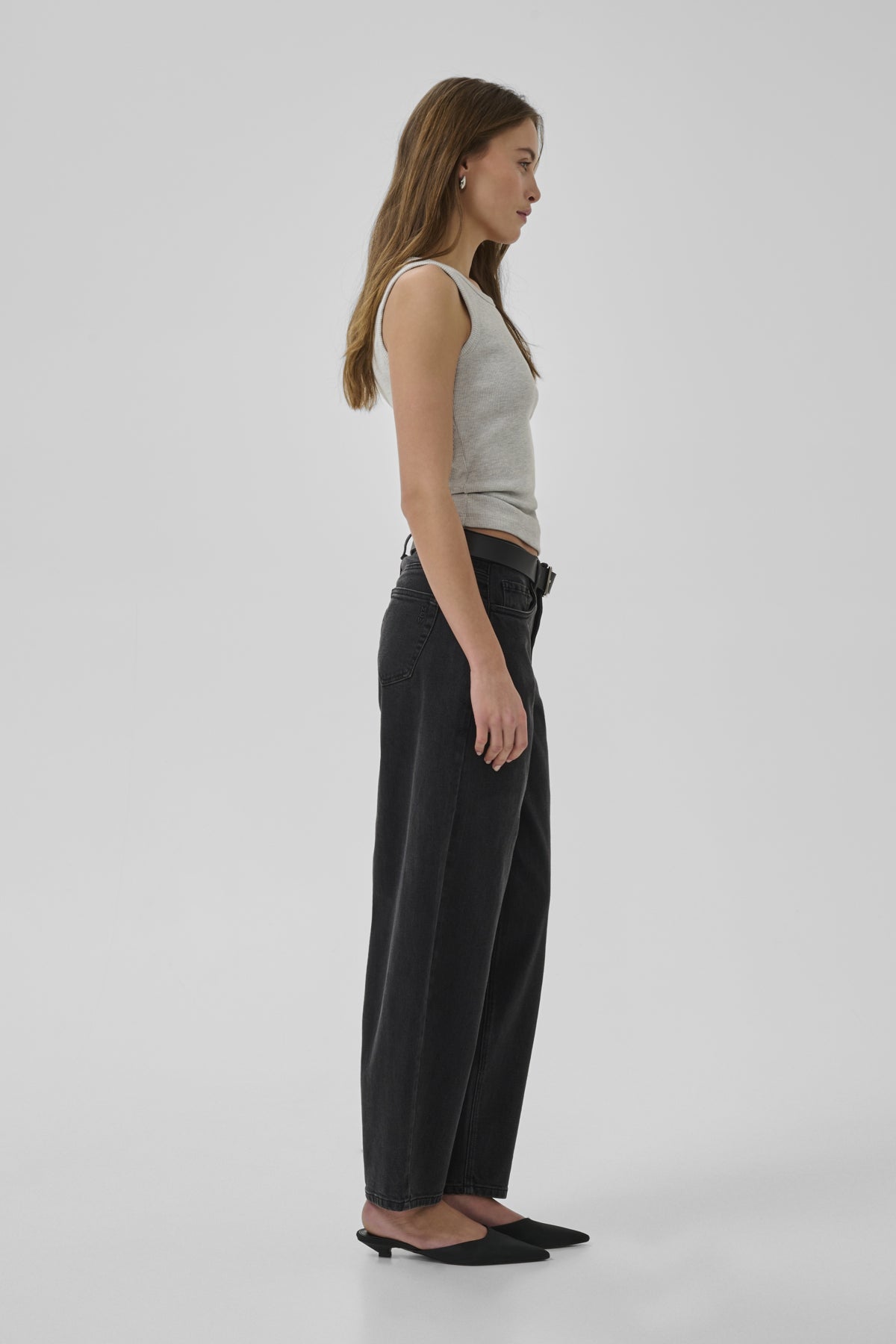 Woman wearing a gray tank top and black pants on a white background