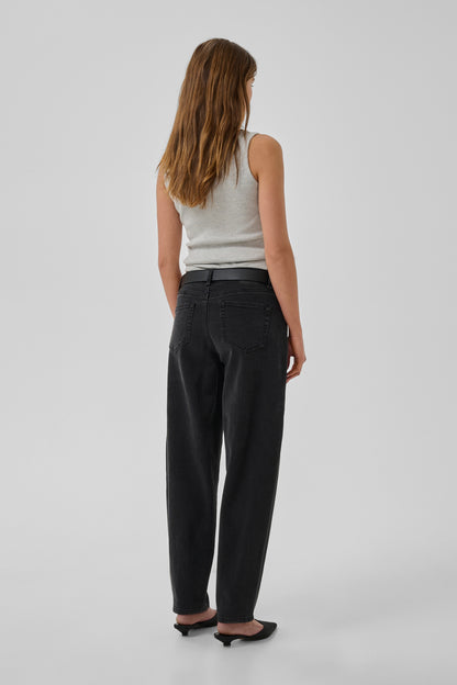 Woman wearing black pants and a white top on a plain background
