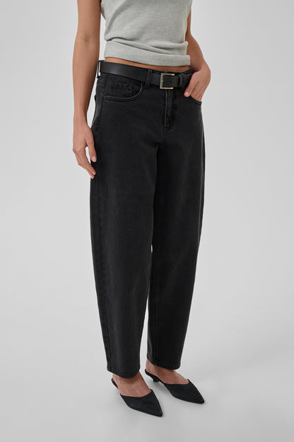 Person wearing black pants with a belt on a plain background