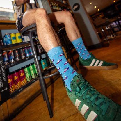 Person wearing blue and green socks with airplane pattern in a bar setting