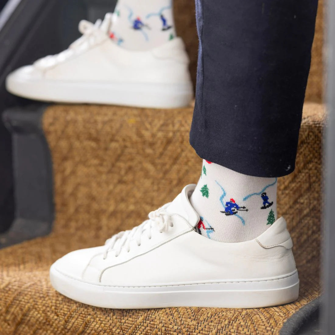 White sneakers with colorful socks featuring skiers on a textured surface.