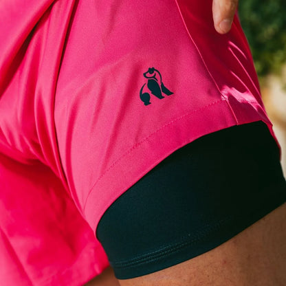 Close-up of a pink shirt with a black logo worn by a person outdoors.