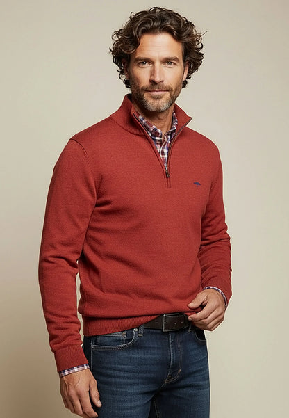 Man wearing a red sweater with a plaid shirt underneath on a beige background
