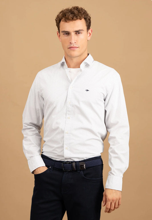 Man wearing a white patterned shirt and dark pants on a beige background