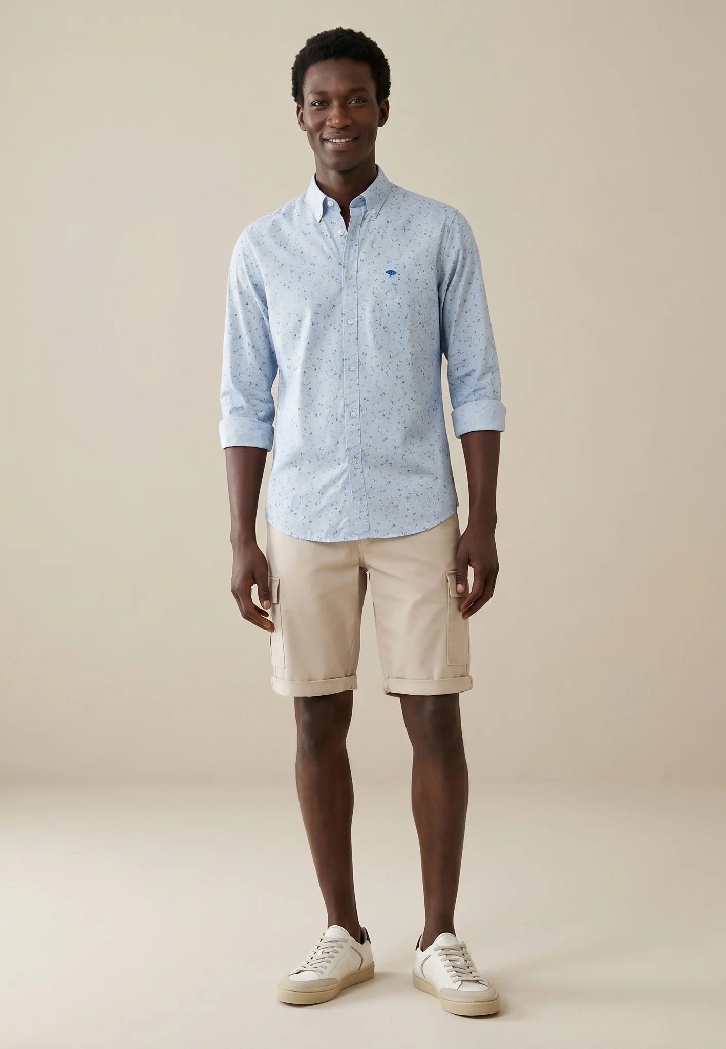 Man wearing a light blue checkered shirt and beige shorts on a beige background