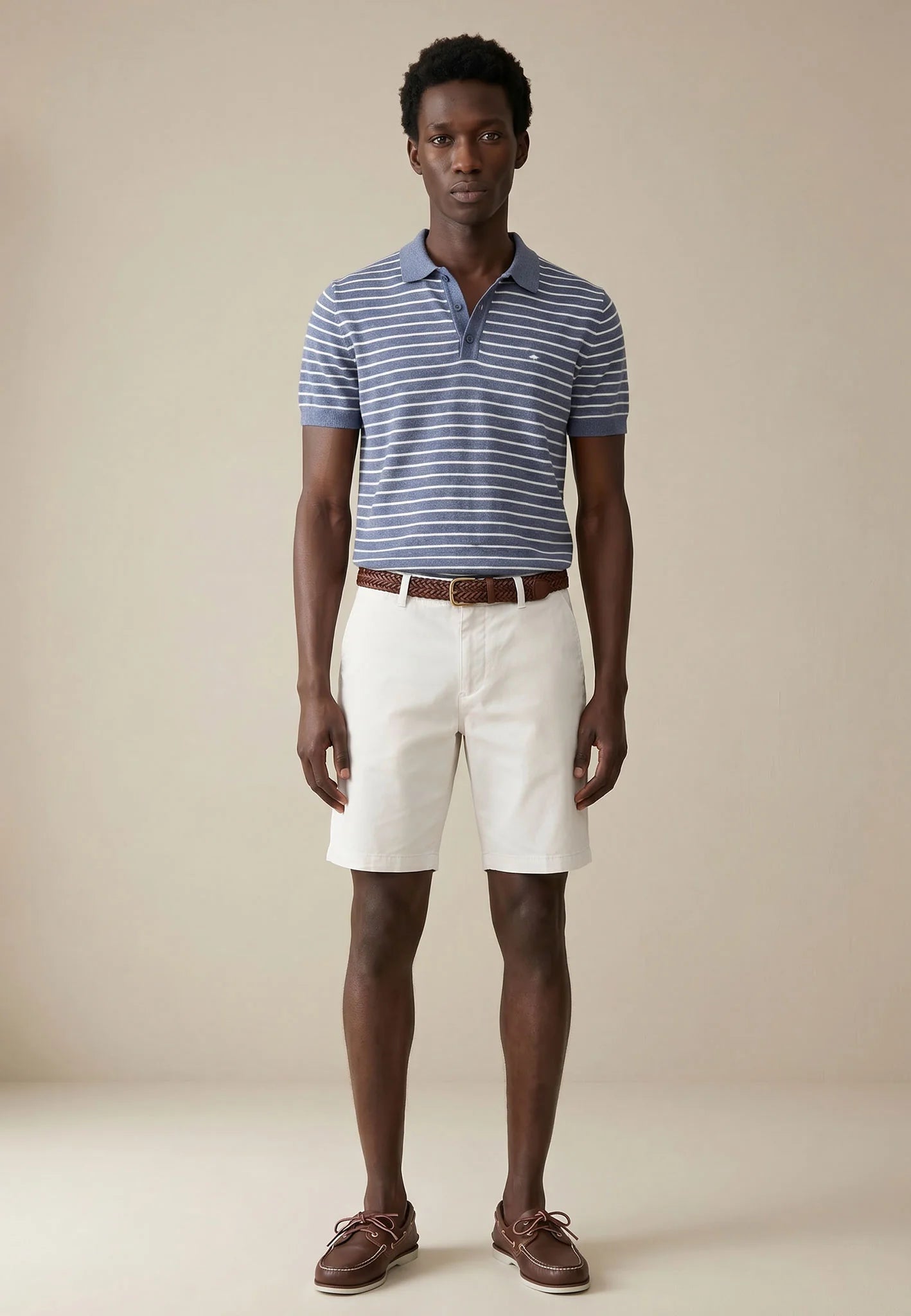 Man wearing a striped polo shirt, white shorts, and brown shoes on a beige background