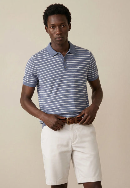 Man wearing a striped polo shirt and white shorts against a beige background