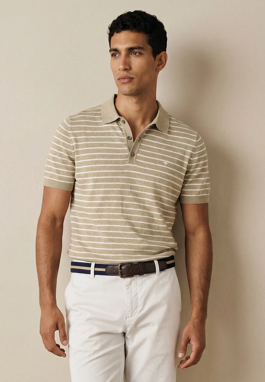 Man wearing a striped polo shirt and white pants against a beige background