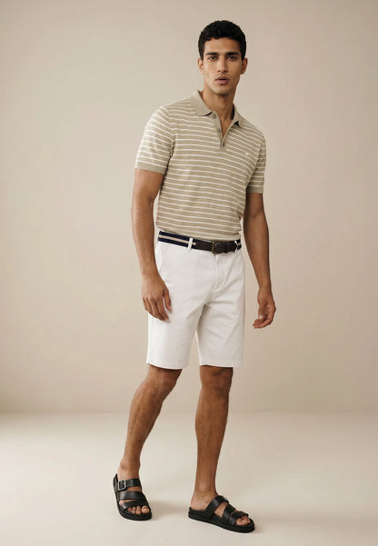 Man wearing a striped polo shirt and white shorts on a beige background