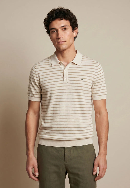 Man wearing a striped polo shirt and green pants against a beige background