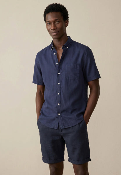 Man wearing a navy blue short-sleeve shirt and shorts on a beige background