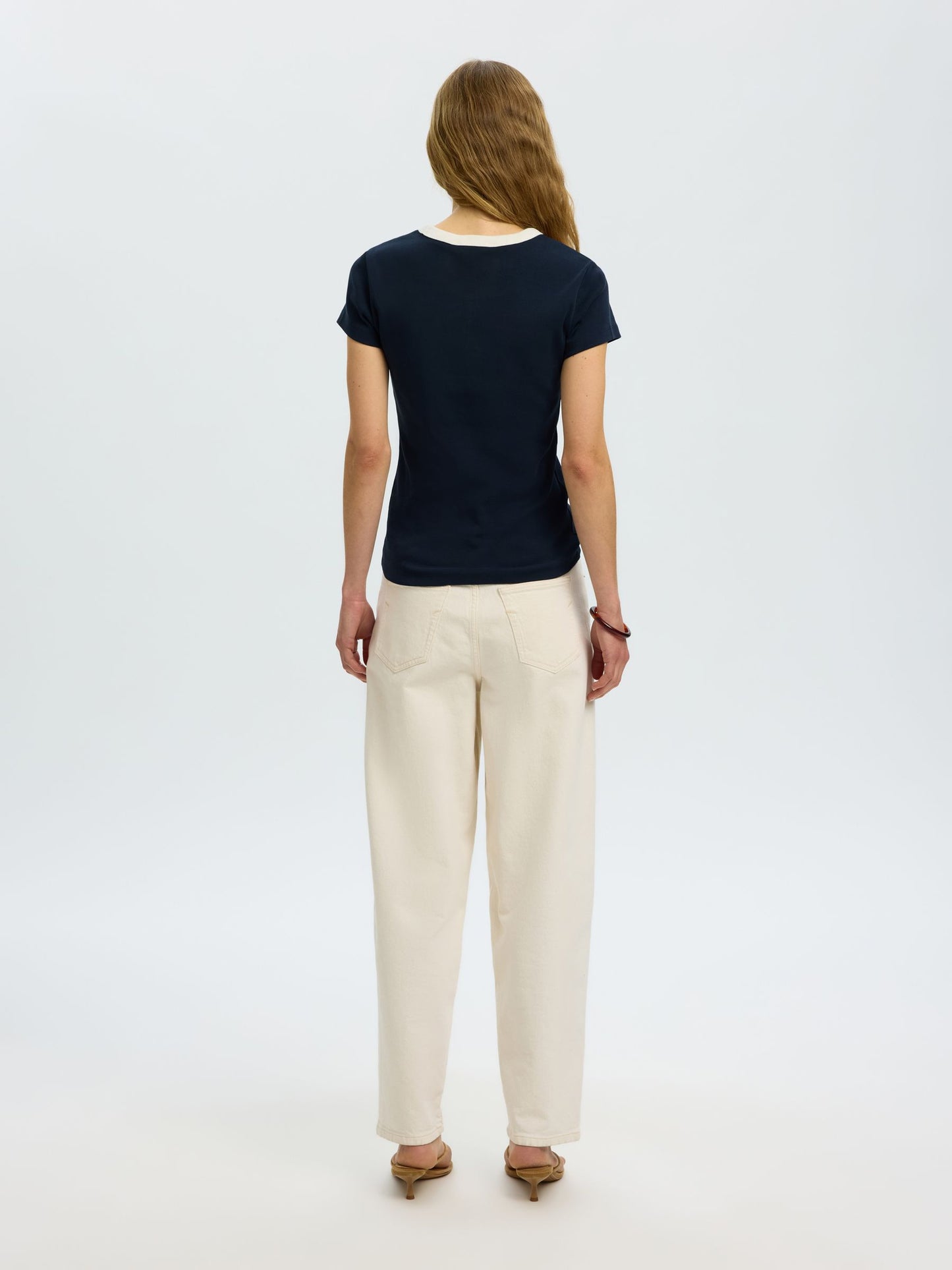 Woman wearing a black t-shirt and beige pants on a white background