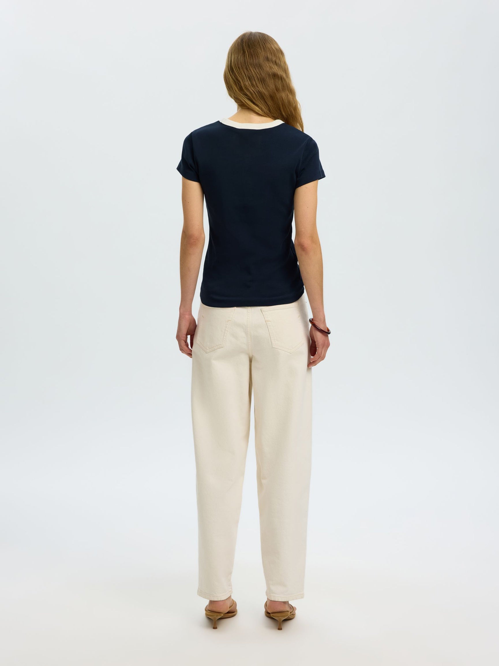 Woman wearing a black t-shirt and beige pants on a white background